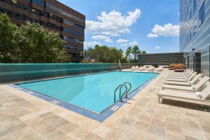 a swimming pool with lounge chairs and a building at Hilton Houston North in Houston