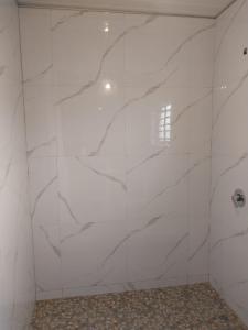 a white tiled wall in a bathroom with a window at Kasuba Apartments in Livingstone
