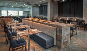 a restaurant with wooden tables and chairs and a bar at Hilton Houston North in Houston