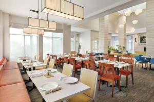 a dining room with white tables and chairs and windows at Hilton Garden Inn Houston/Clear Lake NASA in Webster