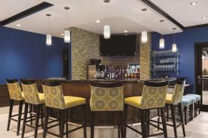 um bar com cadeiras amarelas e uma parede azul em Hilton Garden Inn Houston Northwest em Houston