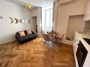 een woonkamer met een zwarte bank en een houten vloer bij Le Petit Palais Notre Dame - Heart of Dijon in Dijon