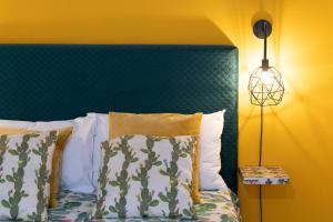 un letto con testiera verde, cuscini e lampada di Cortile Pace a Catania