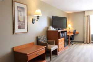 Habitación de hotel con TV, silla y escritorio. en Hampton Inn & Suites Thibodaux, en Thibodaux