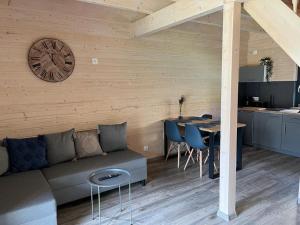 a living room with a couch and a clock on the wall at Nowe Domki Letniskowe in Pobierowo