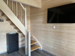 a room with a tv and a staircase with a wall at Nowe Domki Letniskowe in Pobierowo