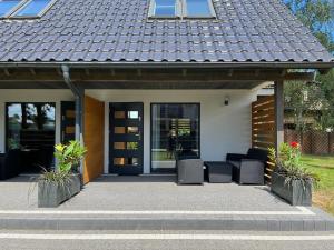 a house with two chairs in front of a door at Nowe Domki Letniskowe in Pobierowo
