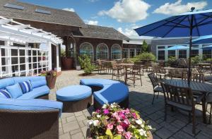 un patio con sillas, mesas y una sombrilla en DoubleTree by Hilton Cape Cod - Hyannis en Hyannis