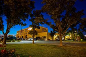 un edificio di notte con alberi in primo piano di DoubleTree by Hilton Wichita Airport a Wichita