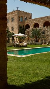 a swimming pool in front of a stone building at Domaine El Htouba in Korba
