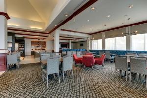 Hilton Garden Inn Indianapolis Airport في بلينفيلد: غرفة طعام مع طاولات وكراسي في مطعم