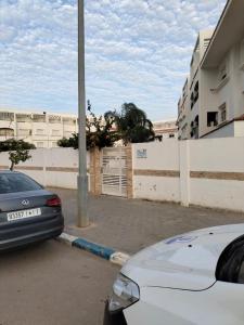 zwei Autos auf einem Parkplatz neben einem Zaun geparkt in der Unterkunft Puerta Del Mar Apartment complex in Tangier