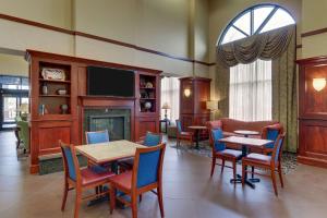 a living room with tables and chairs and a fireplace at Hampton Inn & Suites Indianapolis-Airport in Indianapolis
