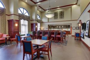 Hampton Inn & Suites Indianapolis-Airport في انديانابوليس: مطعم بطاولات وكراسي وبار