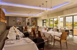 un restaurante con mesas y sillas blancas y ventanas en DoubleTree by Hilton Lincoln, en Lincoln