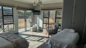 a bedroom with a bed and a chair and windows at Skylight Guest House in Harrismith