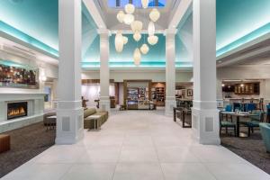 a lobby of a hotel with columns and a fireplace at Hilton Garden Inn Islip/MacArthur Airport in Ronkonkoma