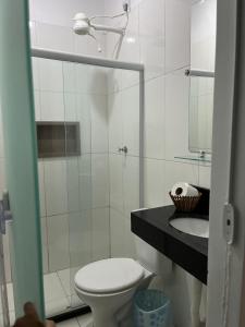 a white bathroom with a toilet and a sink at Pousada Timbalada in Morro de São Paulo