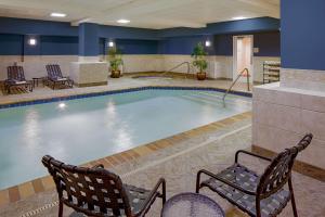 - une piscine dans une chambre d'hôtel avec 2 chaises devant dans l'établissement Hilton Garden Inn Jackson Downtown, à Jackson