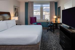 um quarto de hotel com uma cama, uma secretária e uma televisão em Hilton Garden Inn Jackson Downtown em Jackson