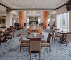 un comedor con mesas, sillas y ventanas en Hilton Garden Inn Jonesboro, en Jonesboro