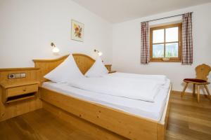 a bedroom with a bed with white sheets and a window at Weber am Gasteig in Reit im Winkl