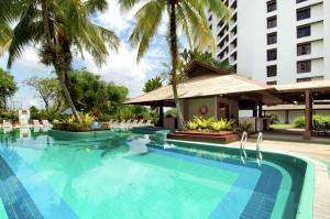 a swimming pool at a hotel with palm trees at Hilton Kuching Hotel in Kuching