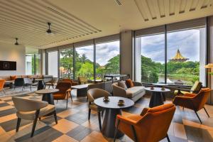 a hotel lobby with tables and chairs and windows at Hilton Kuching Hotel in Kuching