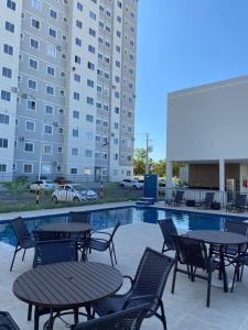 a pool with tables and chairs next to a building at Apês Palmeira Dourada - Centro de Palmas e Aromaterapia in Palmas