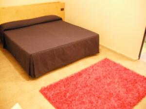 a bed in a room with a red rug at Albergo Ristorante Saverino in Valderice