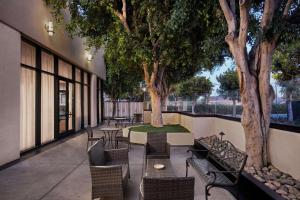 um pátio com mesas, cadeiras e árvores em DoubleTree by Hilton Los Angeles Norwalk em Norwalk
