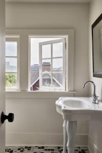 ein weißes Badezimmer mit Waschbecken und Fenster in der Unterkunft Blind Tiger Asheville in Asheville + 52 Fotos