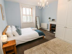 a white bedroom with a bed and a chandelier at The Old Post Office at Holmfirth in Holmfirth