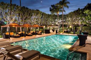 a large swimming pool with lounge chairs and trees at DoubleTree by Hilton Carson in Carson