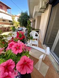 uma varanda com flores cor-de-rosa e um banco branco em Nikoleta downtown apartment em Lefkada