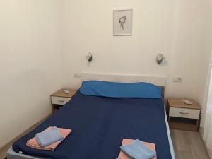 a bedroom with a bed with blue sheets and two tables at Villa History in Crikvenica
