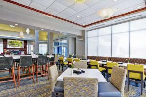 a dining room with tables and chairs and windows at Hilton Garden Inn Conway in Conway