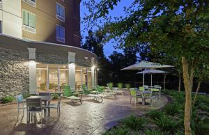 a patio with tables and chairs and an umbrella at Hilton Garden Inn West Little Rock in Little Rock