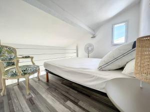 een witte slaapkamer met een groot bed en een stoel bij Maison 6 couchages Saint Cyprien in Saint-Cyprien