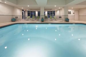 a large swimming pool in a hotel lobby with tables and chairs at Hilton Garden Inn West Little Rock in Little Rock