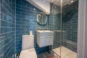 a blue tiled bathroom with a toilet and a sink at Myrtle Cottage in Friston +30 photos