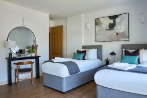 2 Betten in einem Zimmer mit einem Tisch und einem Spiegel in der Unterkunft Kew Bridge by Viridian Apartments in Kew Bridge
