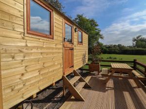 a wooden cabin with a picnic table on a deck at The Oak Hut in Whitchurch