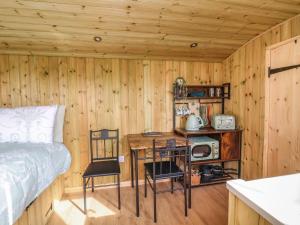 1 dormitorio con 1 cama y pared de madera en The Oak Hut en Whitchurch