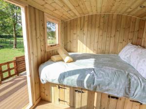 a bed in a wooden cabin with a window at The Oak Hut in Whitchurch
