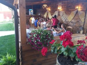 grupa ludzi siedzących w restauracji z kwiatami w obiekcie CASUTELE VADULUI w mieście Vadu