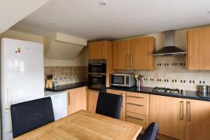 a kitchen with a wooden table and a white refrigerator at Colliers House in Abercanaid