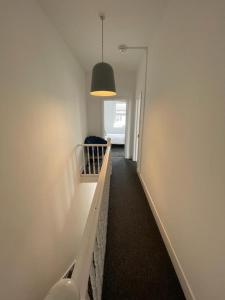 a hallway with a stairway with a light and a stair case at House by Araminta in Hounslow