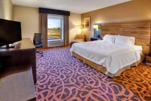 um quarto de hotel com uma cama e uma televisão de ecrã plano em Hampton Inn Midland em Midland