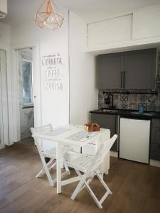 a white kitchen with a white table and chairs at La Stella Sea House in Torvaianica
